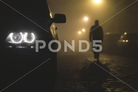 The car headlight with a walking man on the background of a fog Stock Photos