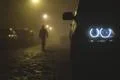 The car headlight with a walking man on a fog background. Evening-night time Photo