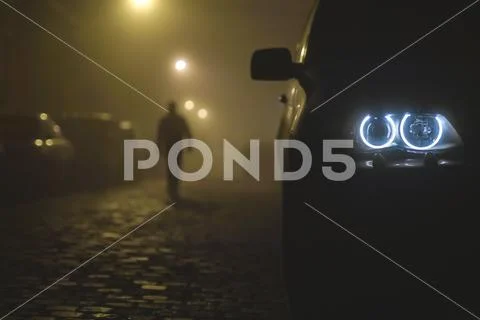 The car headlight with a walking man on a fog background. Evening-night time Stock Photos