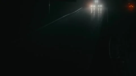 Car Headlights Approaching on a Dark Rainy Highway at Night During Travel Stock Footage 331164299