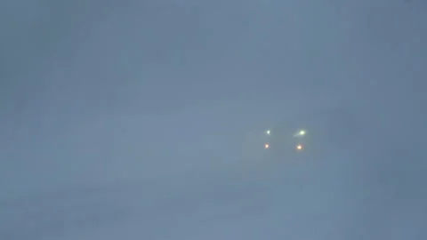 Car with headlights drives through snow storm Stock Footage 169528640