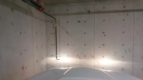 Car headlights illuminating empty concrete underground parking wall, copy space Stock Footage 332961244