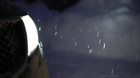 Car headlights lighting falling snow in the evening Stock Footage 146548717