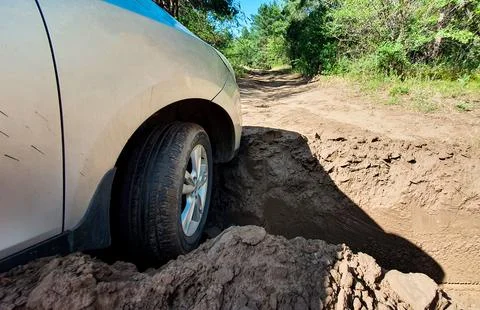 The car hit the front wheel in a deep hole on the road in the forest strip. Stock Photos