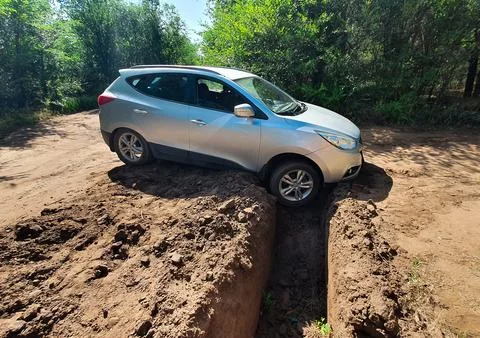 The car hit the front wheel in a deep hole on the road in the forest strip. Stock Photos