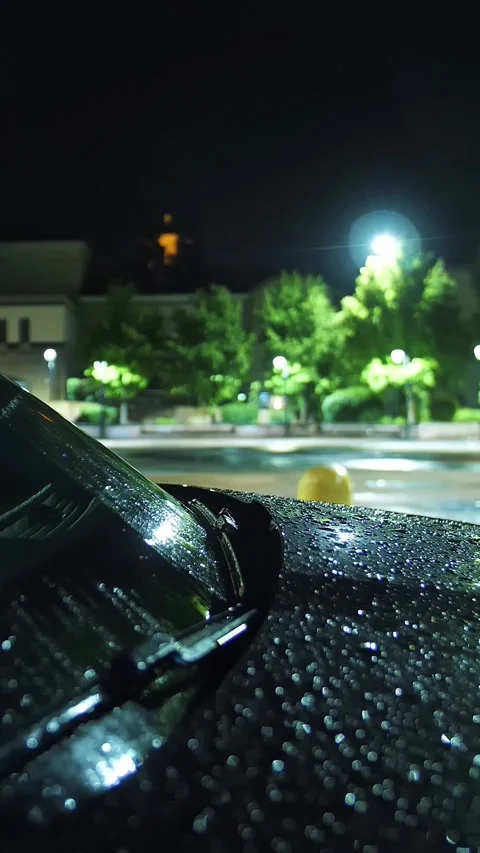 Car hood in raindrops. Rain. Puddle of water. City at night. Rain Drop With Stock Footage 310182790