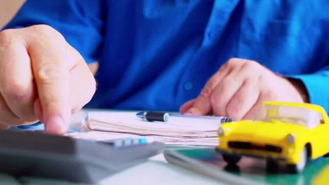 Car insurance agent using calculator and filling policy document Stock Footage 337673421