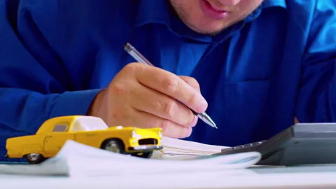 Car insurance agent writing data in policy document at office desk Stock Footage 337671042