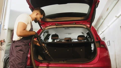 Car interior detailing concept. Young bearded man in uniform doing chemical Stock Footage 233992422