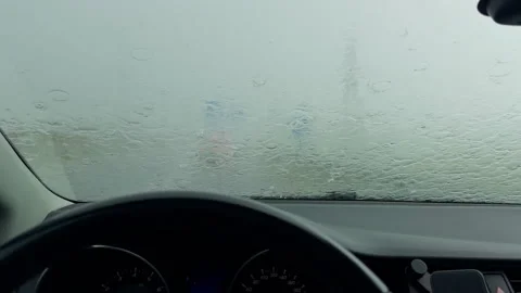 Car interior facing rain soaked windshield during heavy storm with blurred road Stock Footage 345454887