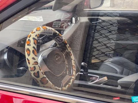 Car interior featuring leopard print steering wheel cover and dashboard det.. Stock Photos