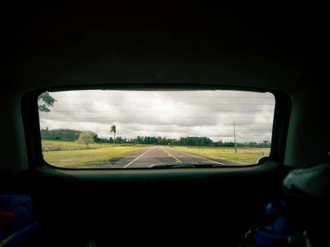 Car interior rear window frames a long, empty road Stock-Fotos