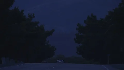 A car with its headlights on comes over the hill Stock Footage 119885853