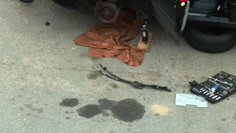 A car jacked up with a wheel removed, a set of tools and auto parts on the Stock Footage 314429391