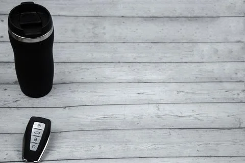 A car key with automatic buttons and a thermocup are black with metal inserts on Stock Photos