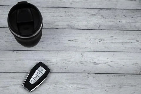 A car key with automatic buttons and a thermocup are black with metal inserts on Stock Photos