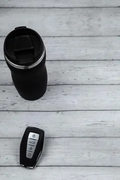 A car key with automatic buttons and a thermocup are black with metal inserts on Stock Photos