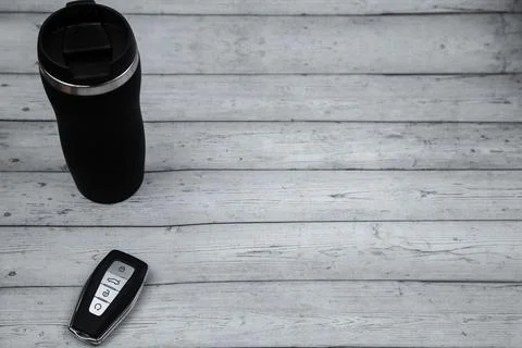 A car key with automatic buttons and a thermocup are black with metal inserts on Stock Photos