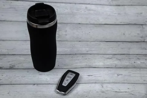A car key with automatic buttons and a thermocup are black with metal inserts on Stock Photos