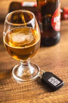 Car key with beer glass on wooden table. Booze driving concept. Drunk drive.. Stock Photos