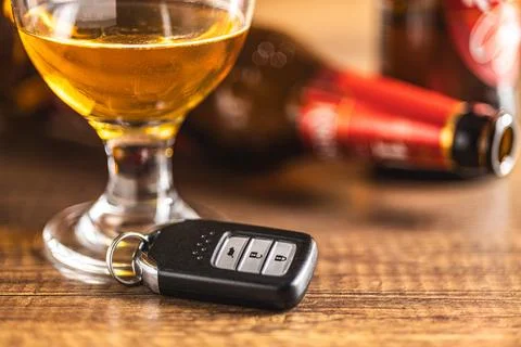 Car key with beer glass on wooden table. Booze driving concept. Drunk drive.. Stock Photos