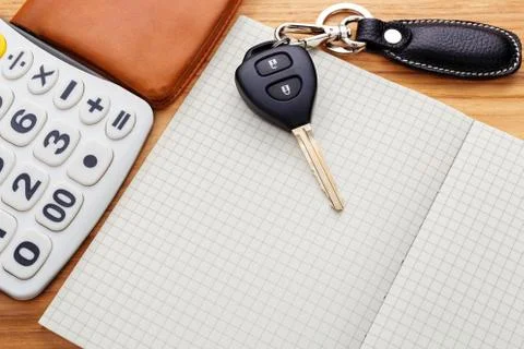 Car key on blank notebook with calculator and pocket money on wood table Stock Photos