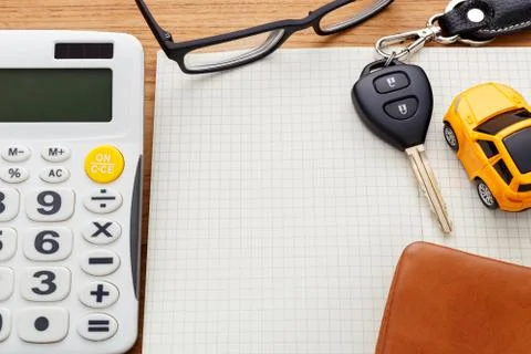 Car key on blank notebook with calculator and pocket money on wood table Foto stock