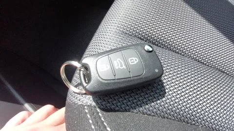 Car key fob with remote control buttons lying on a black fabric car seat Stock Footage 335072500