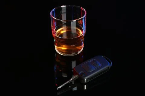 Car key near glass of alcohol on black table. Dangerous drinking and driving Stock Photos