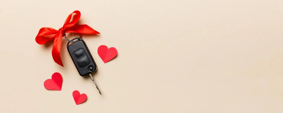 Car key with a red bow and a heart on Colored table. Giving present or gift.. Stock Photos