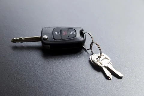 Car key on top of a black table with natural light. Key with buttons to lock  스톡 사진