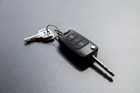 Car key on top of a black table with natural light. Key with buttons to lock  스톡 사진