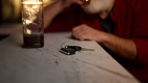 Car keys on bar counter as man drinks liquor before driving, DUI risk concept Stock Footage 342520370