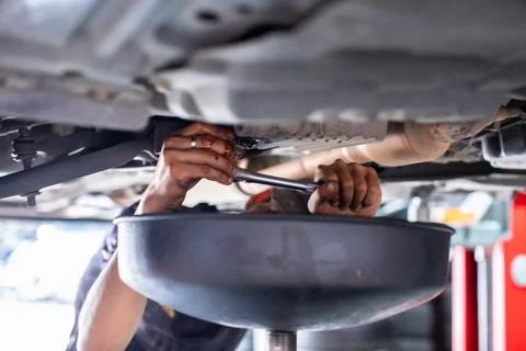 Car maintenance process: draining old engine oil at service station. Stock Photos