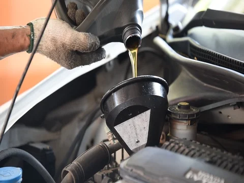 Car maintenance servicing mechanic pouring new oil lubricant into the car engine Stock Footage 77633406