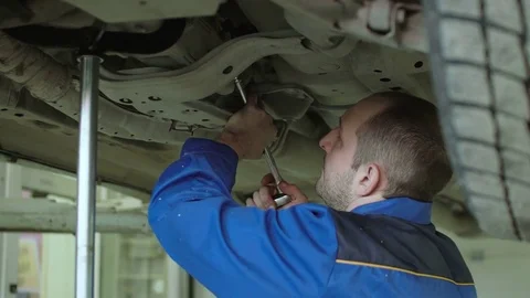 Car mechanic is checking car suspension on lifted crossover car in blue overalls Video stock 74860180