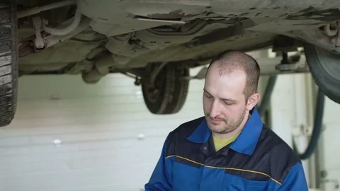 Car mechanic is checking car suspension on crossover in car repair service Video stock 74864906