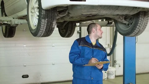 Car mechanic is checking car suspension on crossover in car repair service Video stock 74867511