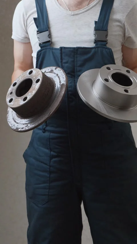Car mechanic comparing old rusty and new brake discs Stock Footage 326142764