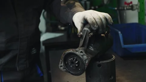 Car mechanic disassembles and repairs a worn out old car part; a car starter Stock Footage 285640883
