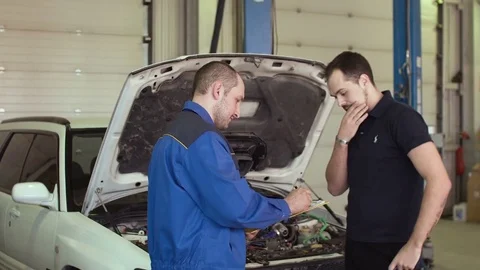 Car mechanic is discussing with client in auto repair service with clipboard Video stock 74604262