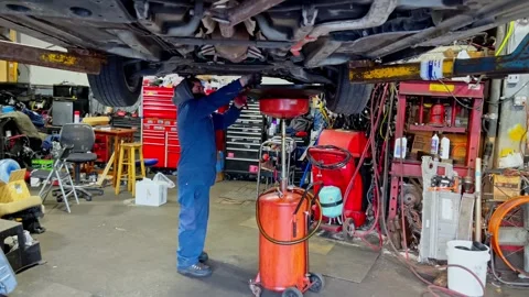 Car mechanic draining engine oil in auto repair shop Stock Footage 335203390
