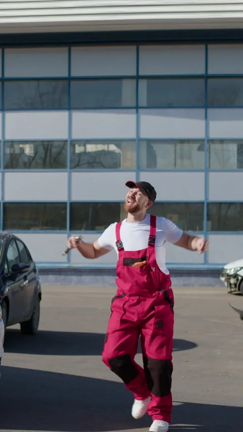 Car mechanic dressed in work clothes and a cap, dancing with good humor because Stock Footage 276262048