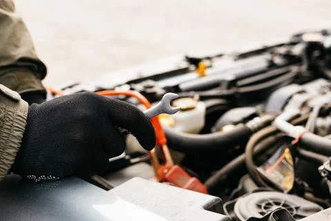 Car mechanic engineer using a wrench in process of fixing a car. Male hands o Stock Photos