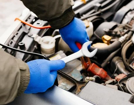 Car mechanic engineer using a wrench in process of fixing a car. Male hands o Stock Photos