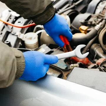 Car mechanic engineer using a wrench in process of fixing a car. Male hands o Stock Photos