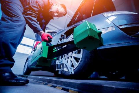 Car mechanic installing sensor during suspension adjustment. Stock Photos