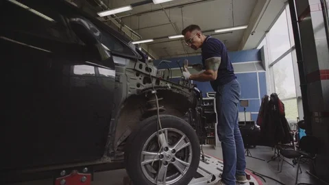Car mechanic performs car body repair (straightens the geometry of the car body. Stock Footage 93134901