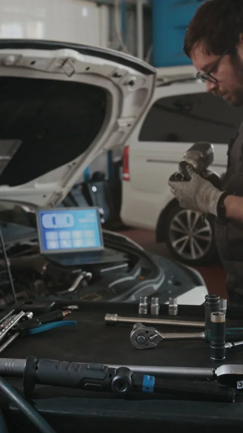 Car Mechanic Picking Up Screwdriver Gun while Performing Engine Diagnostics Stock Footage 329478291
