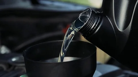Car mechanic pours oil into the engine closeup. Stock Footage